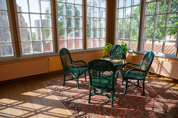 Camera luminosa in cottage con sedie in vimini di rattan e tavolo. Grandi finestre e luce solare
. - Foto, immagini