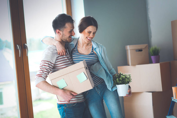 Happy young couple unpacking or packing boxes and moving into a new home - Fotó, kép