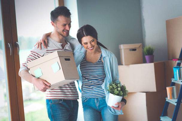 Happy young couple unpacking or packing boxes and moving into a new home - Foto, Imagem