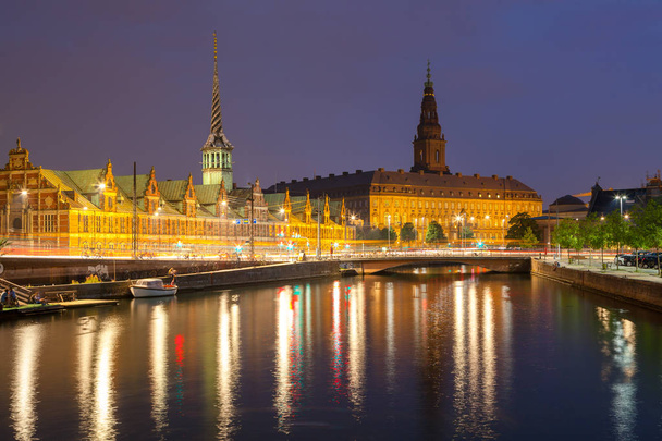 Vista noturna do Palácio de Christiansborg e do edifício da Bolsa de Valores sobre o canal em Copenhague
. - Foto, Imagem