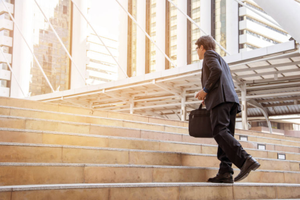 Бізнесмен йде по сходах з міським фоном, бізнесмени йдуть до концепції успіху
. - Фото, зображення