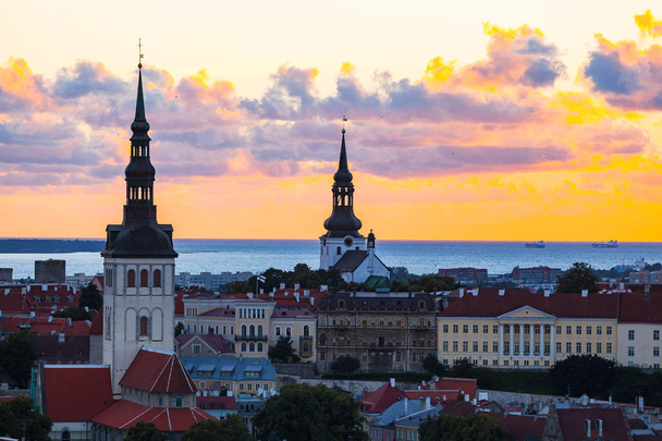 Puesta de sol naranja sobre el casco antiguo de Tallin, Estonia. Torres catedrales y edificios medievales vista aérea
. - Foto, Imagen