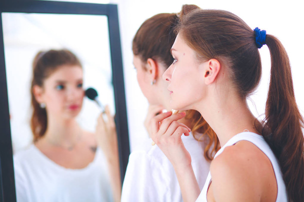 Beautiful girls looking in the mirror and applying cosmetic with a big brush - Fotoğraf, Görsel