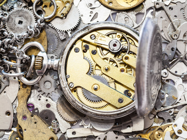 relógio de bolso de prata aberta em montão de peças de reposição
 - Foto, Imagem