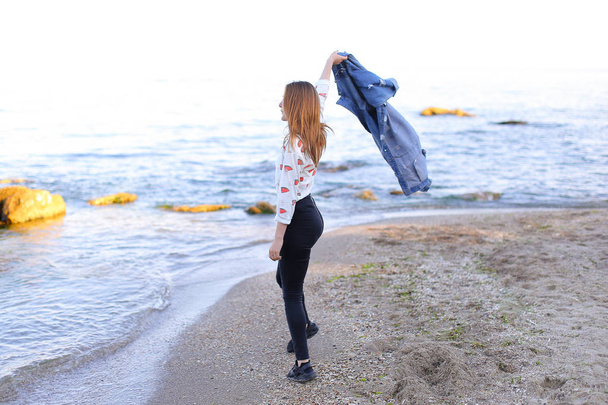 Очаровательная девушка идет вдоль берега и веселые дураки вокруг на песке
 - Фото, изображение