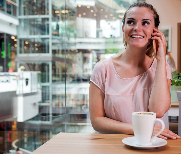 Girl talking on mobile phone in cafe at shopping mall - Φωτογραφία, εικόνα