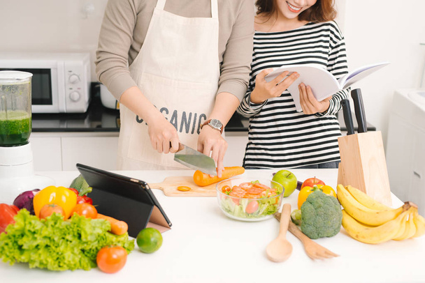 Happy couple in kitchen together. Man cutting vegetables and mak - Фото, изображение