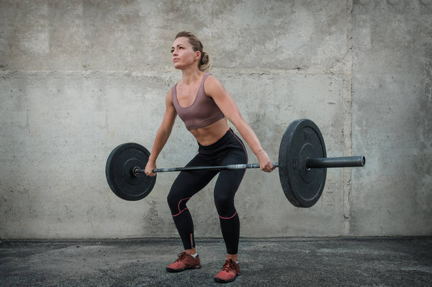 Chica joven haciendo ejercicio con una barra de pesas
 - Foto, Imagen