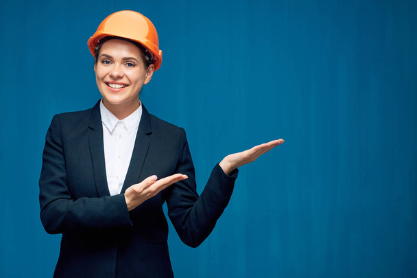 Constructora presentando las manos vacías. Retrato de mujer de negocios sonriente constructora en azul
. - Foto, imagen