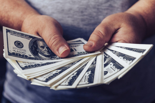 Ανθρώπινο χέρι εκμετάλλευση τραπεζογραμματίων δολαρίων ΗΠΑ που απλώνονται από ανεμιστήρα, καθιστώντας μετρητά χρήματα σχέδιο επιτυχίας - Φωτογραφία, εικόνα