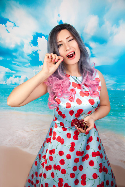 alegre jovem pin up menina comer doce cereja de pé sozinho
 - Foto, Imagem