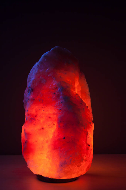 beleuchtete Himalaya-Salzlampe auf Holztisch - Foto, Bild