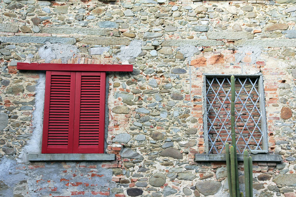 Egy ablak zárt piros ablak redőnyök és egy fallal körülvett, őszinte ablak egy ház falán - Fotó, kép
