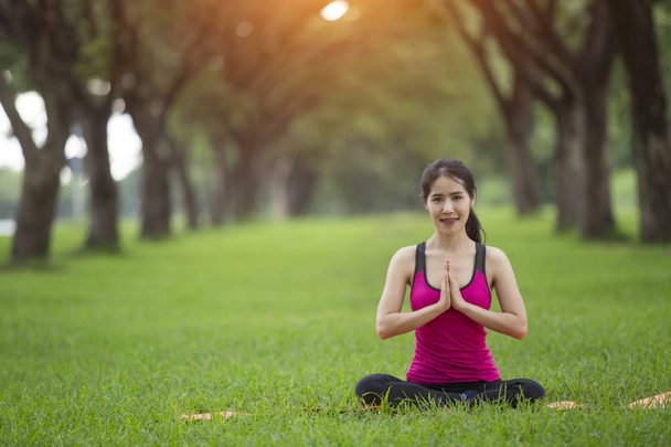 молодая женщина практикующая йогу в парке - Фото, изображение