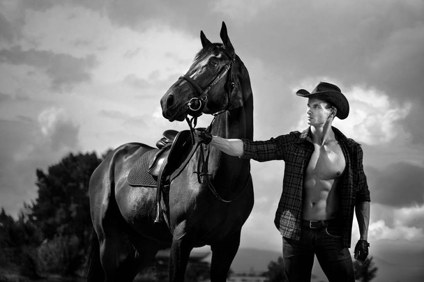 Macho man handsome cowboy and horse on the background of sky and water. - Фото, зображення