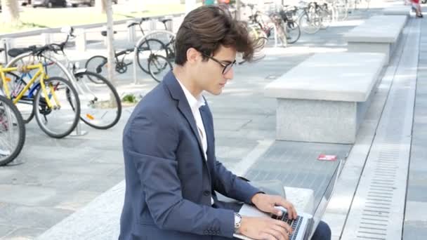 Handsome young man working at computer outdoor - Video, Çekim