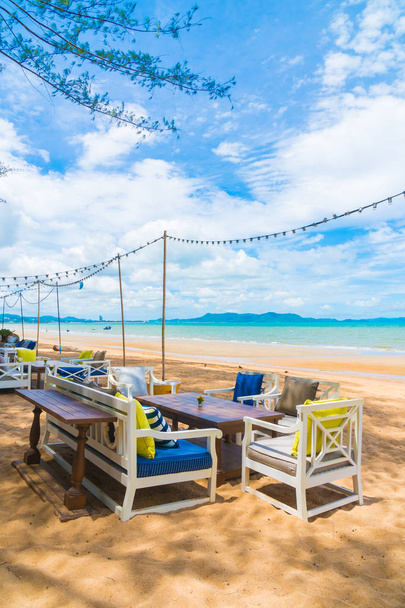 Стул и обеденный стол на пляже и море с голубым небом
 - Фото, изображение