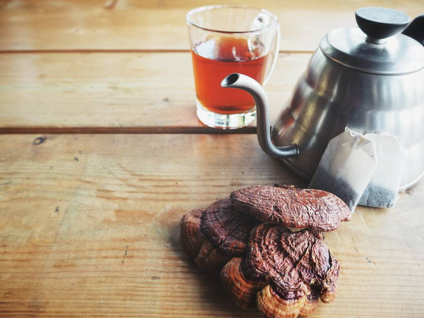 закрытый вид на прозрачный чай Ganoderma и гриб Ling zhi на деревянном столе
 - Фото, изображение
