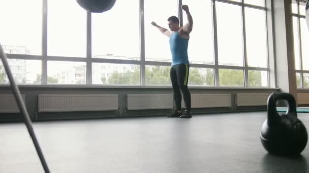Фитнес-клуб - молодой сильный мужчина делает упражнения для разминки в тренажерном зале
 - Кадры, видео