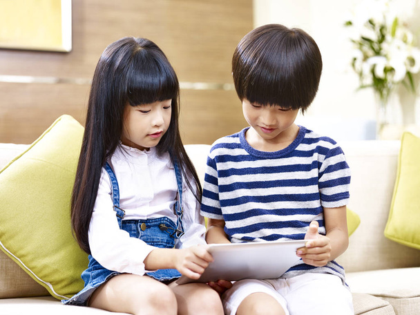 Ασιατικές αδελφός και αδελφή χρησιμοποιώντας ψηφιακό tablet στο σπίτι - Φωτογραφία, εικόνα