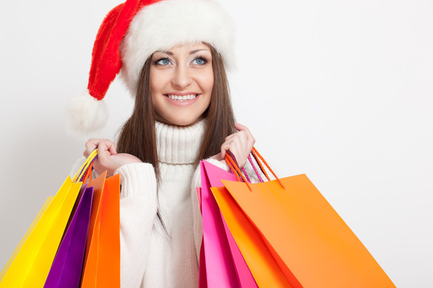 Brunette woman in santa hat holding shopping bags - Foto, Imagem