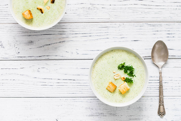 Groene gezonde crème soep met broccoli, cashewnoten, crackers en peterselie - Foto, afbeelding