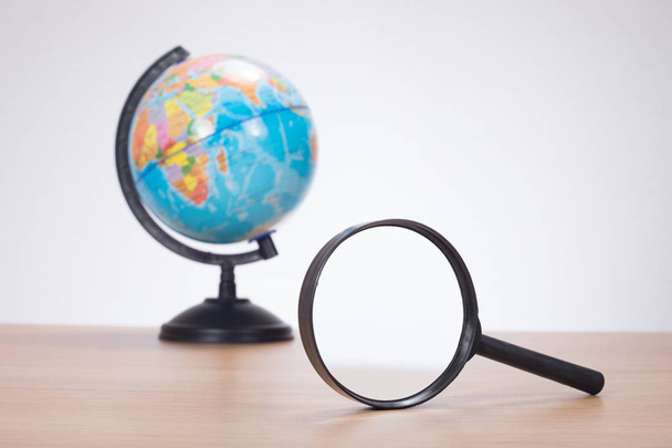 Magnifying glass with globe in background - Photo, Image