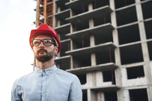 Portrait of modern civil engineer on background of building construction - 写真・画像