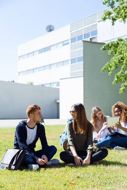 Happy students sitting outside on campus at the university. - Φωτογραφία, εικόνα