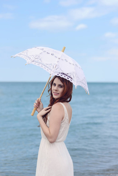 portrait of redhead woman at beach with umbrella - Photo, Image