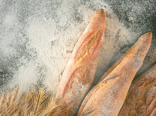Fresh baguettes on the table sprinkled with flour. - Photo, Image