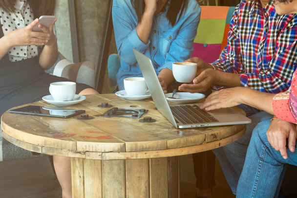 Čtyři ženy se setkávají sdílením informací z notebooku a pitím kávy v kavárně s teplým světlicovým tónem - Fotografie, Obrázek