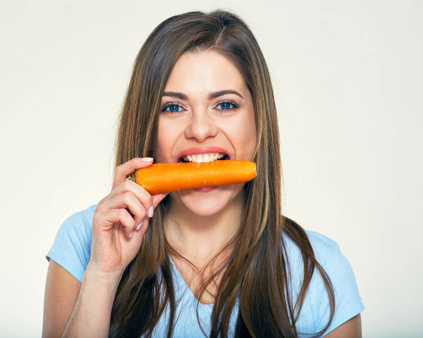 Young woman holdin carrot in teeth. - Fotografie, Obrázek