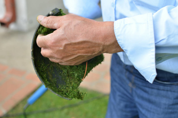 Man's hand cleaning lawn trimmer - Foto, Imagem