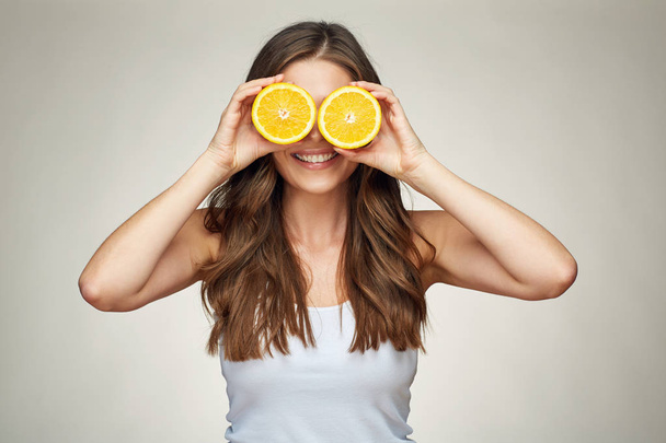 Smiling woman holding two half og oranges fruit ahead of eyes.  - Zdjęcie, obraz