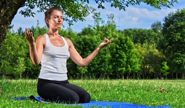 Молодая женщина во время медитации йоги в парке
 - Фото, изображение