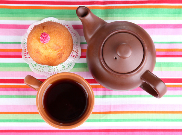 Top view of cup of tea and teapot on colorful tablecloths - 写真・画像
