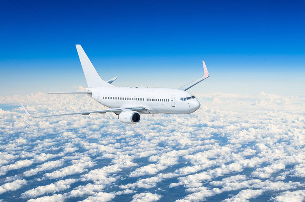 Λευκό αεροπλάνο πετά ψηλά στον ουρανό τα σύννεφα μπλε ουρανό - Φωτογραφία, εικόνα