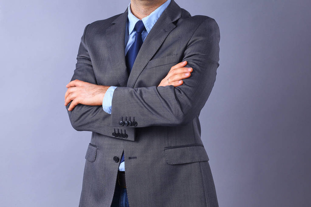 Young businessman standing with arms crossed, isolated on gray background - Foto, immagini