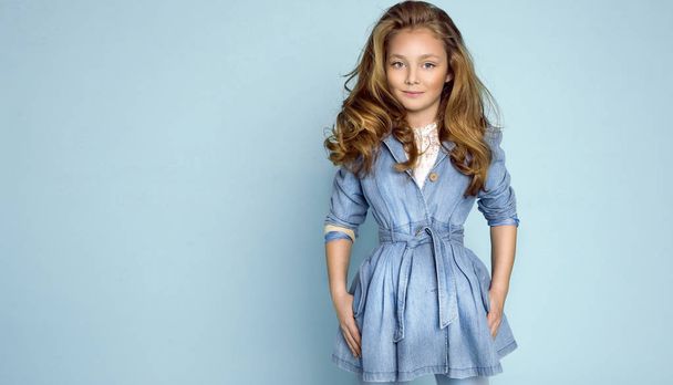 schöne süße kleine blonde Mädchen in Jeans auf blauem Hintergrund - Foto, Bild