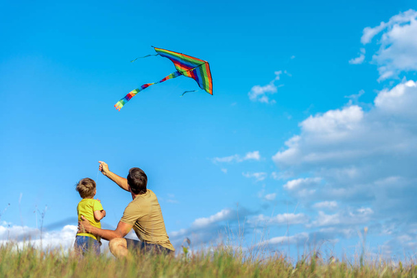Cheerful boy and man playing with flying toy on field - Fotoğraf, Görsel