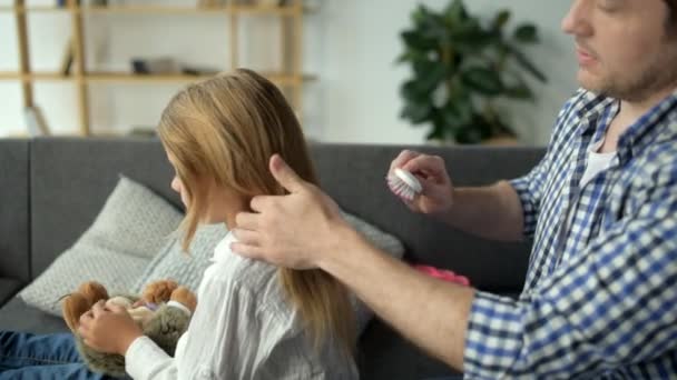 Positive father brushing hair of his nice daughter - Materiał filmowy, wideo