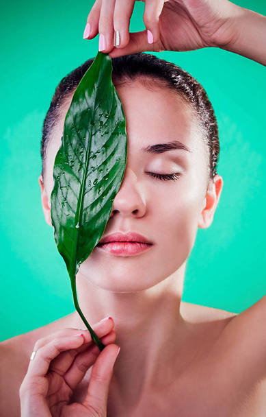 Woman covering her eyes with a leaf. Organic cosmetics concept - Φωτογραφία, εικόνα