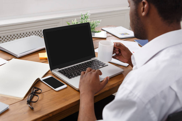 Afro-Amerikaanse zakenman in kantoormachines op laptop - Foto, afbeelding