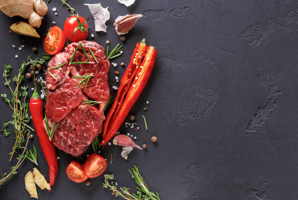 Rib eye steak, kruiden en groenten op zwarte achtergrond - Foto, afbeelding