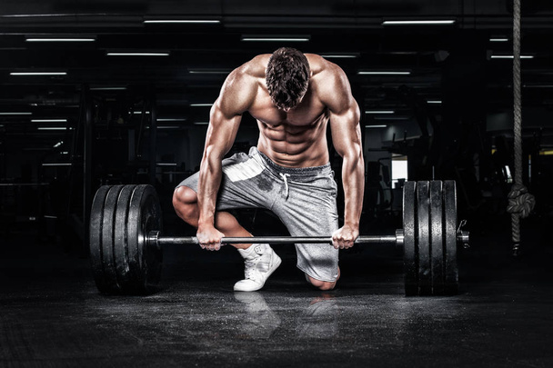 Muscular young fitness sports man workout with barbell in fitness gym - Fotoğraf, Görsel