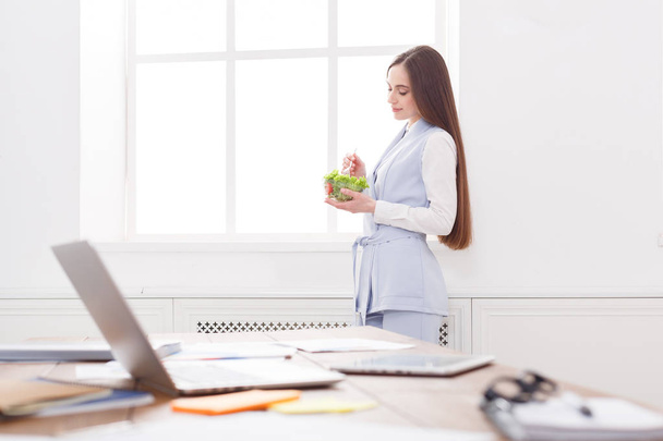 Jovem mulher de negócios comendo salada no escritório
 - Foto, Imagem