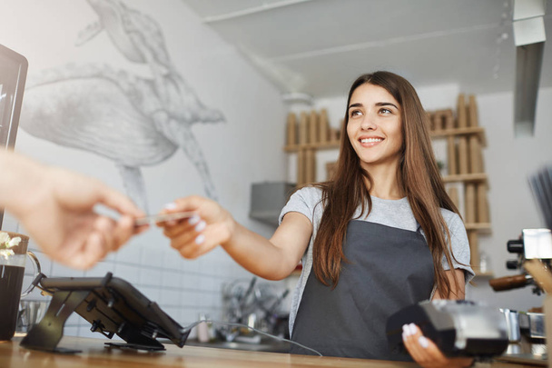 Female barista interacting with customer using a bank terminal to process and acquire credit card payments. - Photo, image