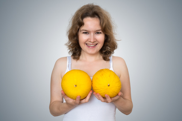 junge schöne Frau hält Melonen in den Händen über ihrer Brust. pl - Foto, Bild