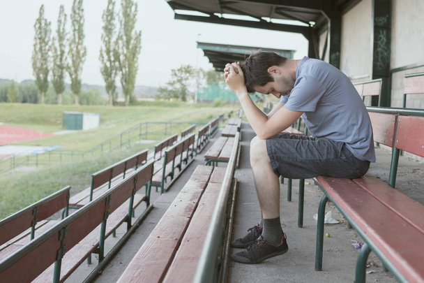 Despair and depressed man is sitting in stadium. Solitary and lo - Zdjęcie, obraz
